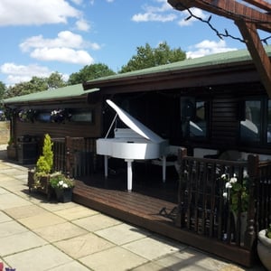 A wedding ceremony outside with the grand piano at Flaxbourne Gardens