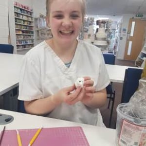 Young girl smiling during making her manikin at one of our Junior workshops.